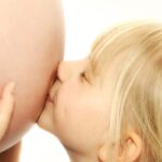 Kind küsst Schwangerschaftsbauch